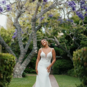 Elegancka koronkowa suknia ślubna typu fit & flare na cienkich ramiączkach z wycięciem i trenem